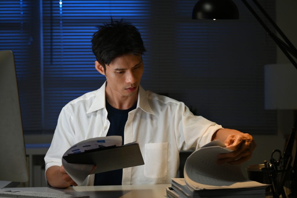 Professional man reviewing documents at desk in office setting.