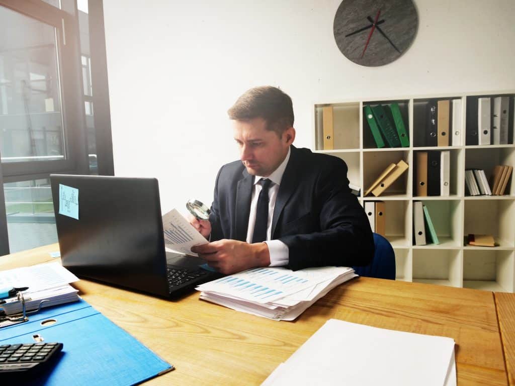 Business professional working at desk with documents and laptop in office.