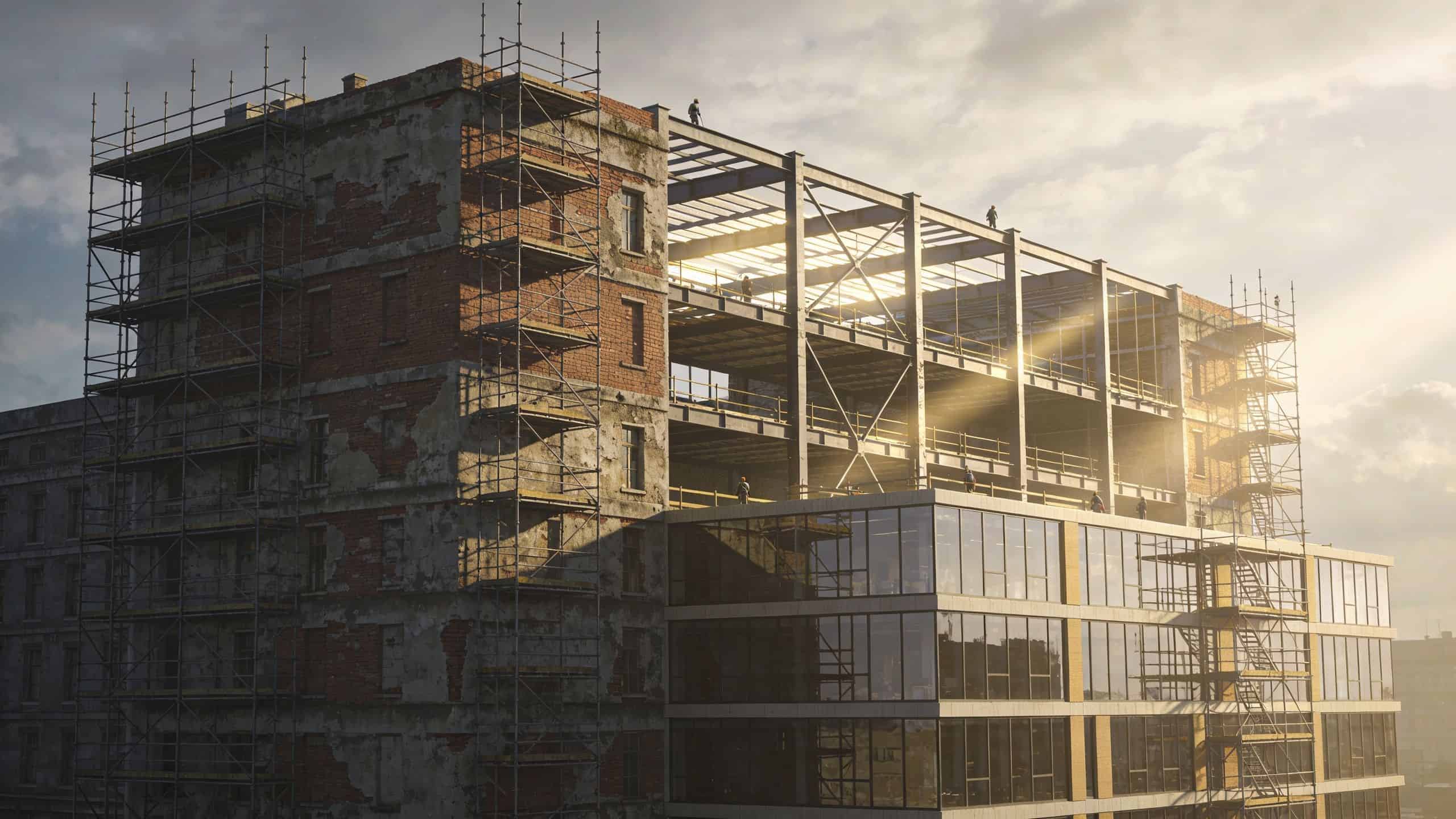 An aging brick building undergoing major construction with modern glass facade extensions under sunlight.