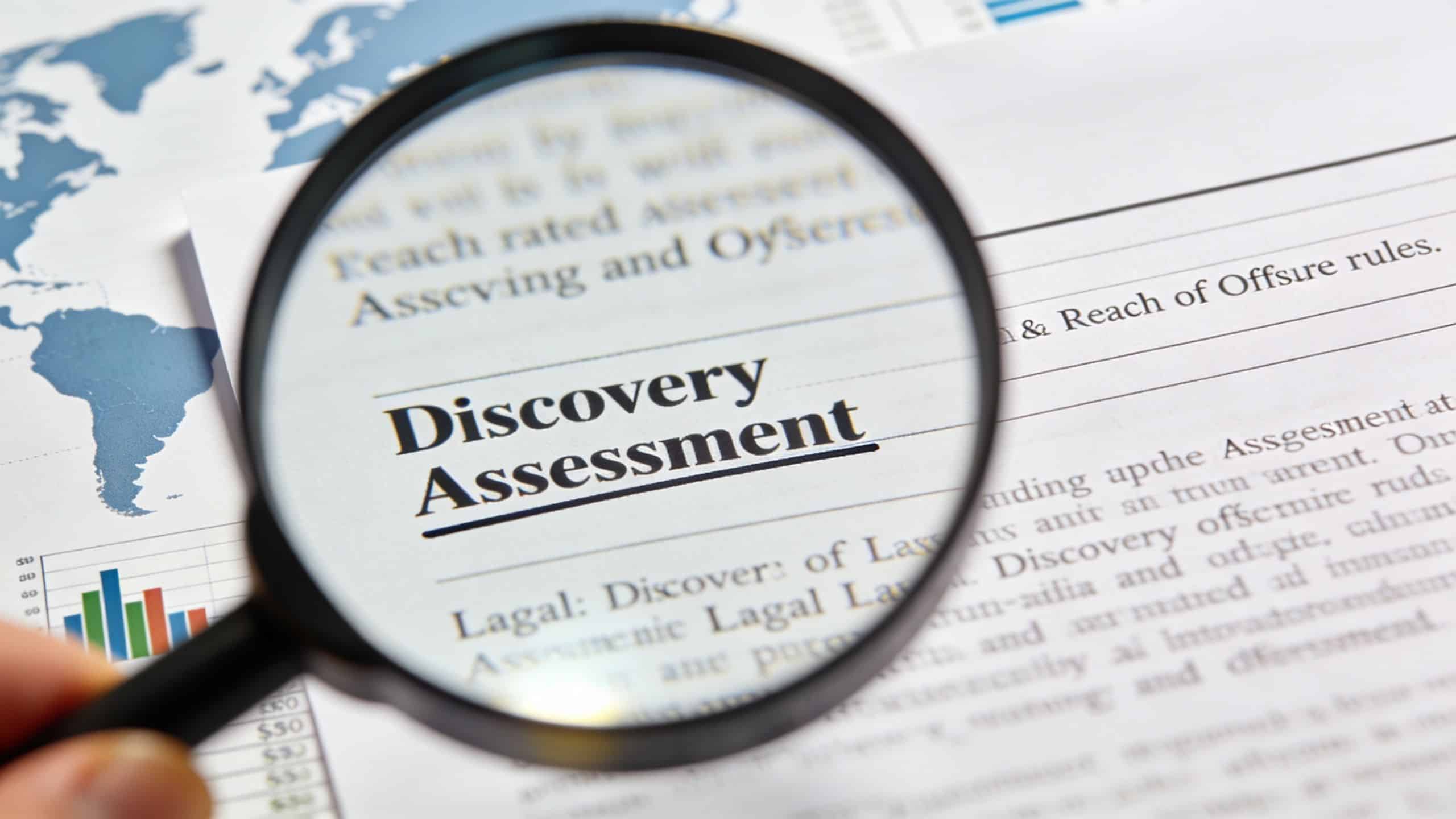 A magnifying glass held over a business document with the words Discovery Assessment highlighted on a report.